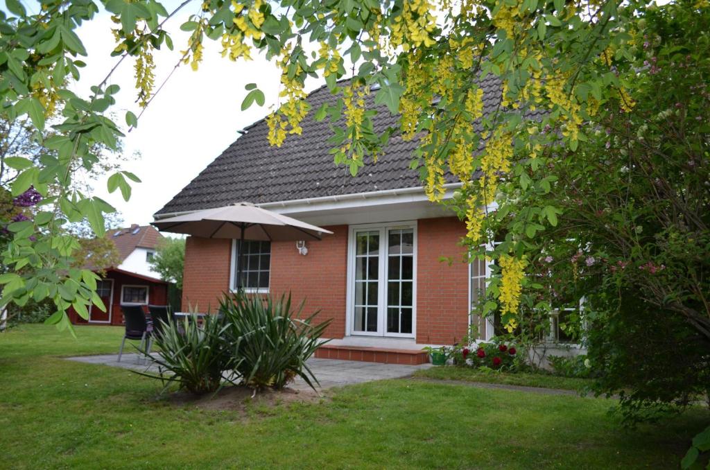 a red brick house with an umbrella in a yard at Ferienhaus Wiking Haus - Terrasse und Garten in Binz