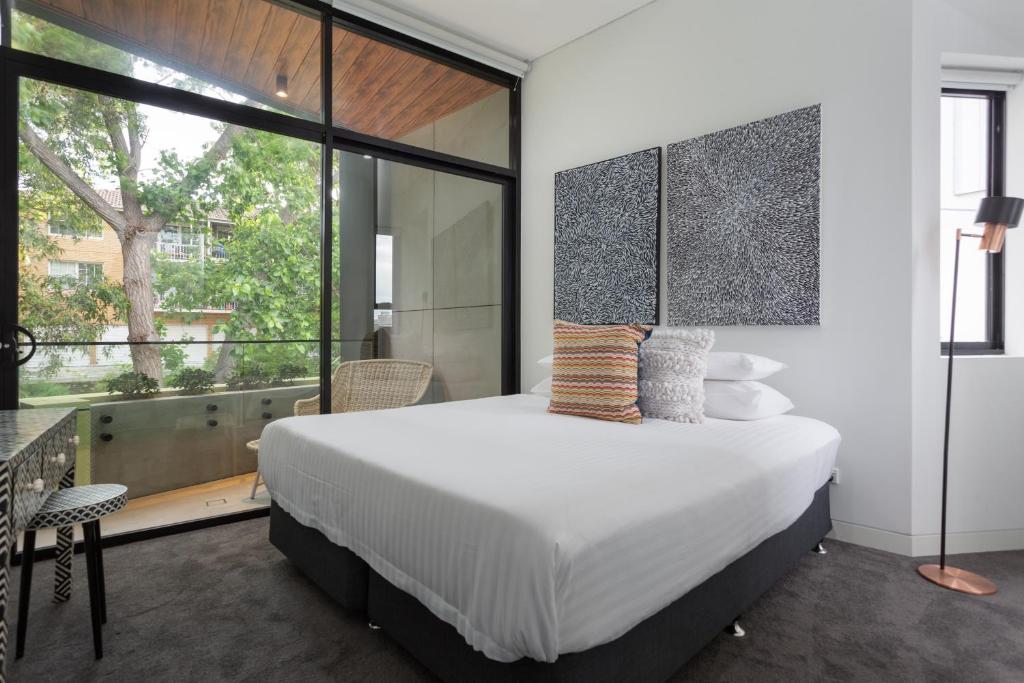 a bedroom with a large bed and a large window at Stylish 2-Bed Apartment with BBQ Patio Near Beach in Sydney
