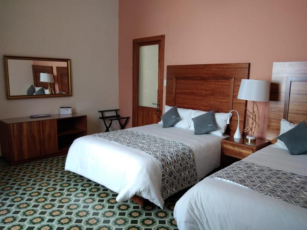 een hotelkamer met 2 bedden en een spiegel bij HOTEL CASA CONSTANZA in San Luis Potosí