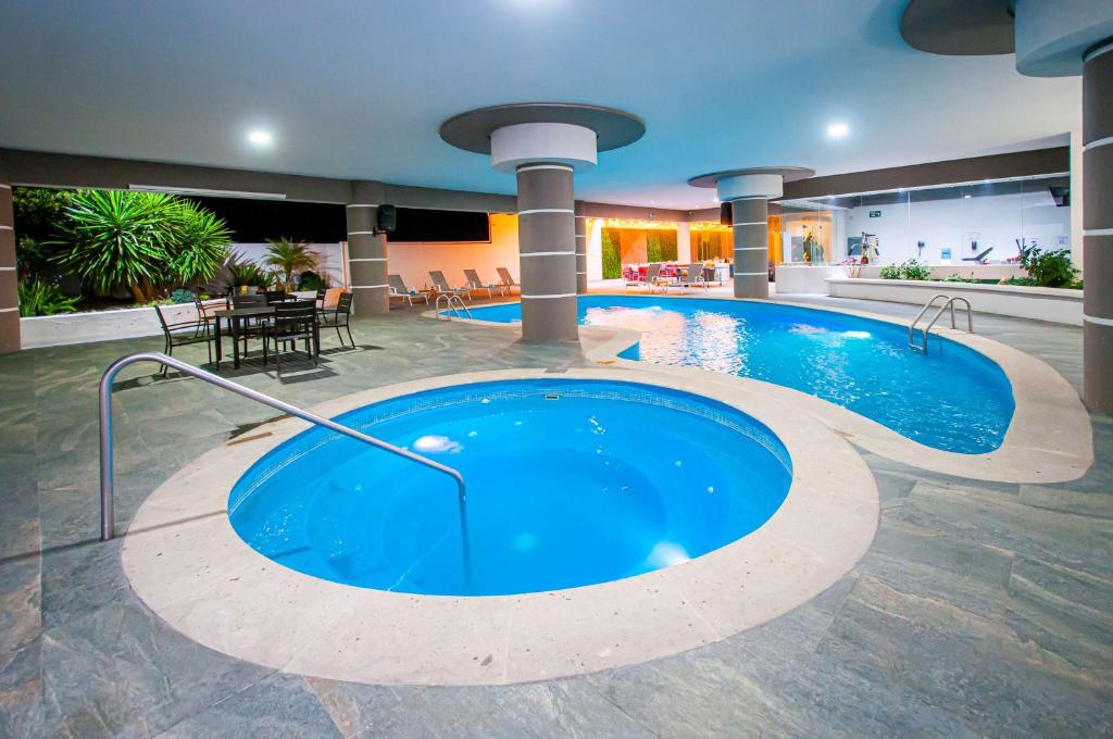 パチューカ・デ・ソトにあるBest Western Plus Santa Cecilia Pachucaのテーブルと椅子付きのホテル内の大きなプールを提供しています。