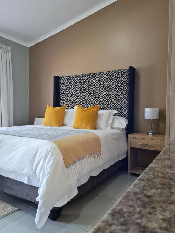 a bedroom with a large bed with yellow pillows at Village Kulture - Guest House in Rustenburg