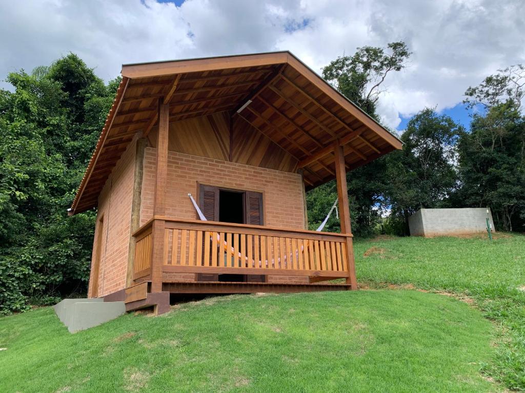 een klein huis met een terras op een grasveld bij Chalés Roma in Santo Antônio do Pinhal