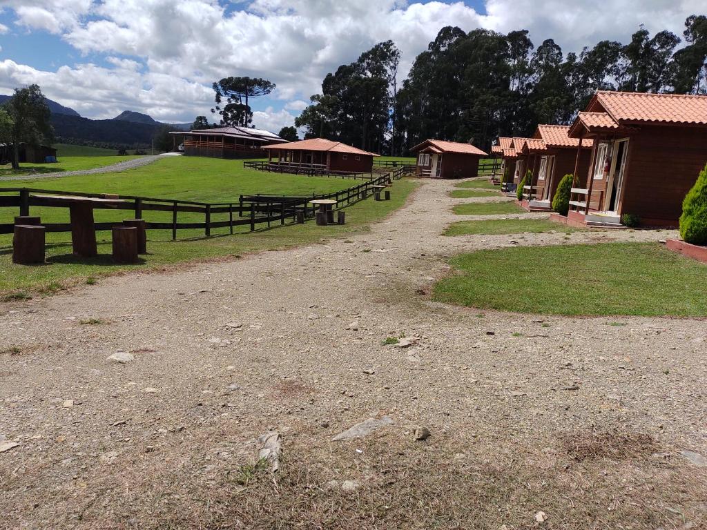 uma estrada de terra ao lado de um grupo de edifícios em Sítio Rancho crioulo em Urubici