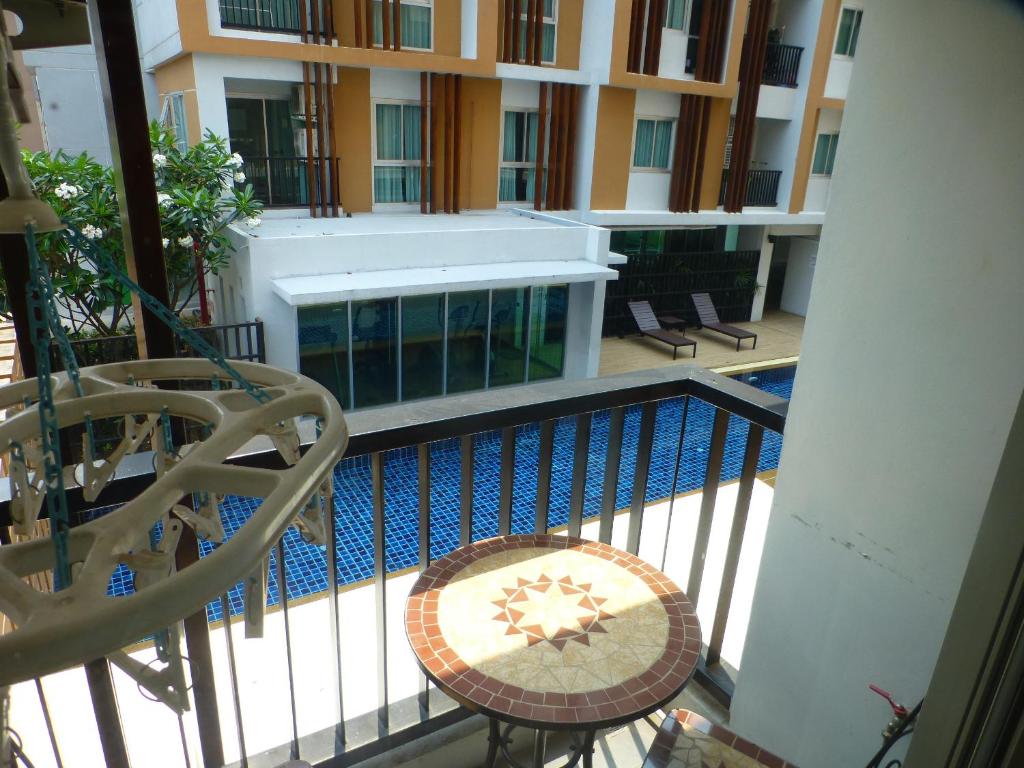 烏隆他尼的住宿－1 Double bedroom Apartment with Swimming pool security and high speed WiFi，阳台设有游泳池、桌子和椅子。