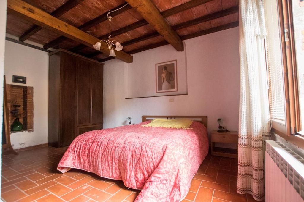 a bedroom with a bed with a red blanket at Apartment immersed in the green of the Maremma in Massa Marittima