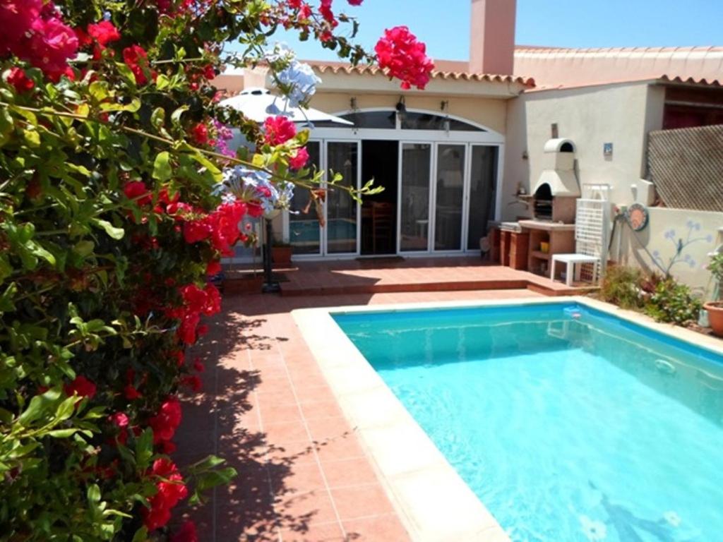 a swimming pool in front of a house with flowers at Lovely CottageAurora in Corralejo