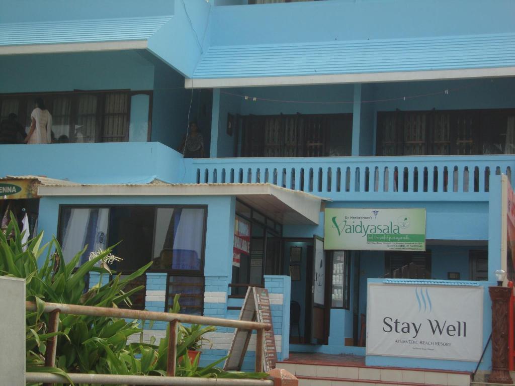 Una casa azul con una buena señal frente a ella. en Stay Well Ayurvedic Beach Resort, en Kovalam