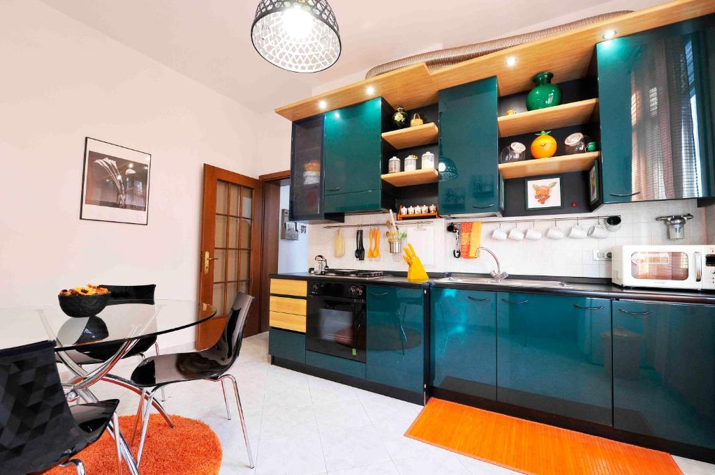a kitchen with green cabinets and a glass table at SantaMarta, the apartment for your Venetian holidays in Venice