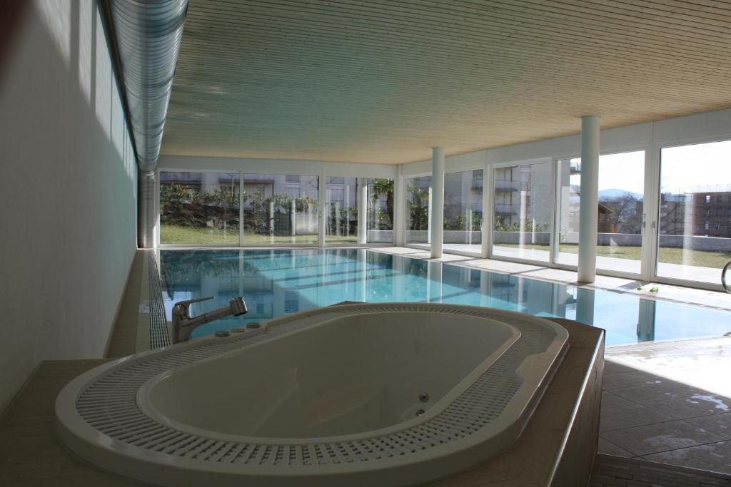 uma grande banheira num edifício com piscina em Indoor Swimming Pool, Sauna, Fitness, Private Gardens, Spacious Modern Apartment em Lugano