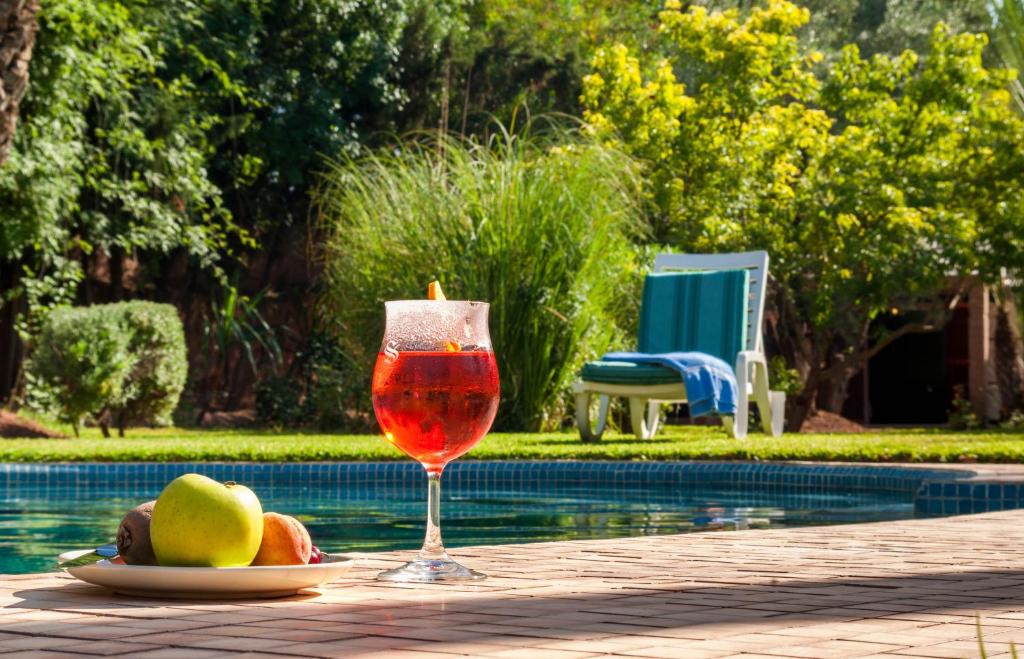 kieliszek wina siedzący na stole obok basenu w obiekcie Charming villa in the heart of Marrakech palm grove w Marakeszu