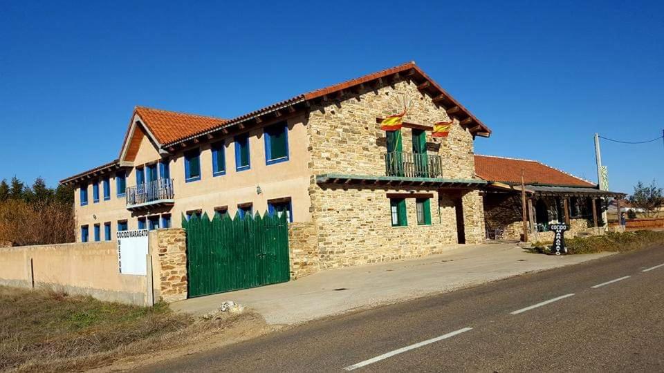 a brick building with green doors on the side of a road at CASARuRAL TIKIKO in Murias de Rechivaldo