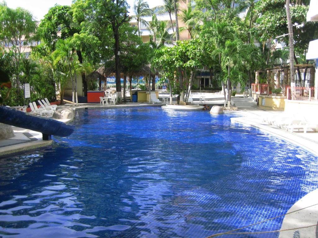 a swimming pool with blue water in a resort at Hotel Delfines Acapulco by NG Hoteles in Acapulco