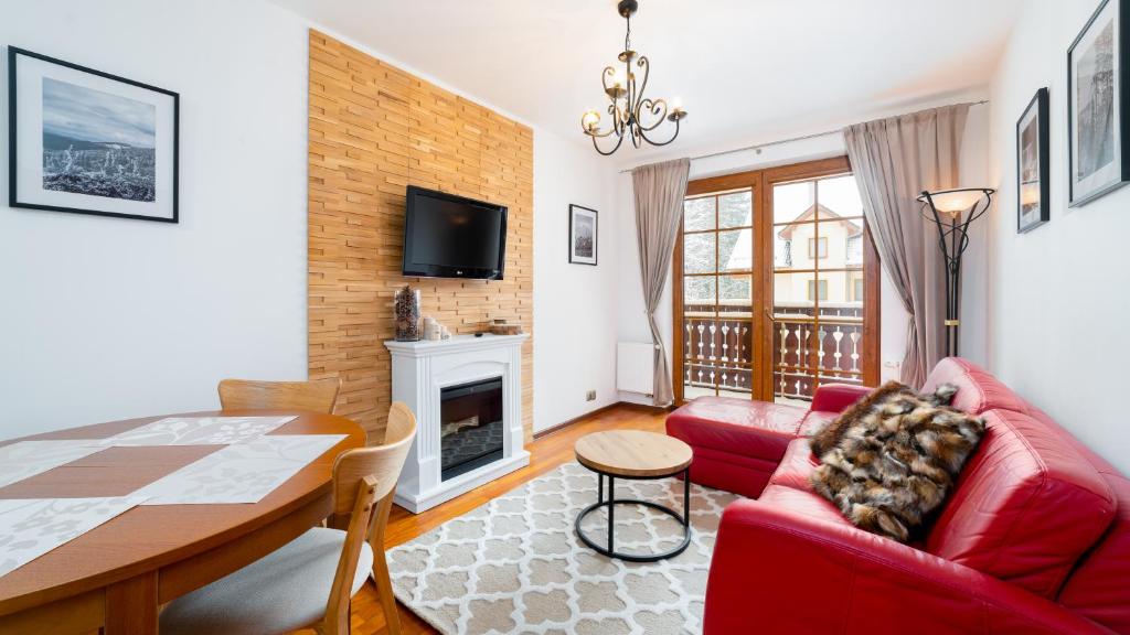 salon z czerwoną kanapą i stołem w obiekcie Apartamenty Sun & Snow Osiedle Podgórze w Szklarskiej Porębie