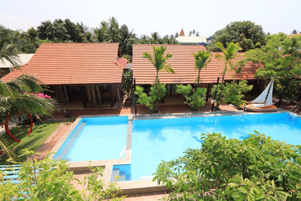 a resort with a large swimming pool and a sailboat at MAY Bungalow in Mui Ne