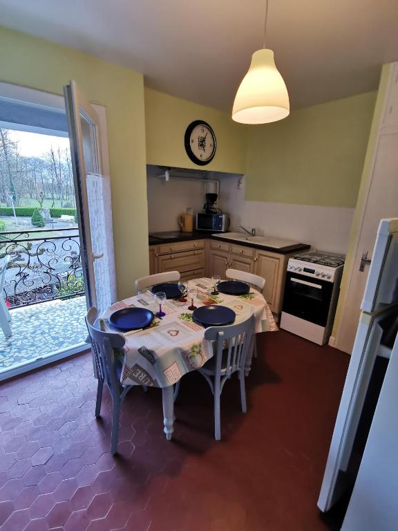 une cuisine avec une table, des chaises et une horloge murale dans l'établissement Appartement Vallée de Luchon, à Salles-et-Pratviel