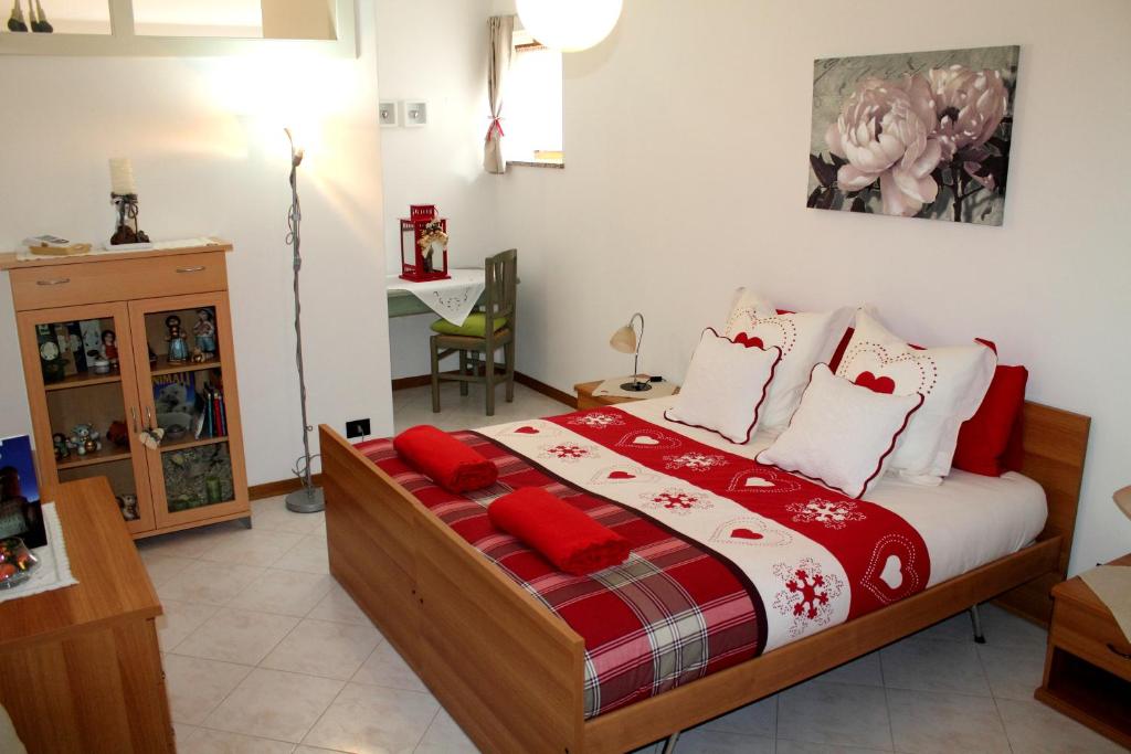 1 dormitorio con 1 cama con almohadas rojas y blancas en Casa Hueller, en Roncegno