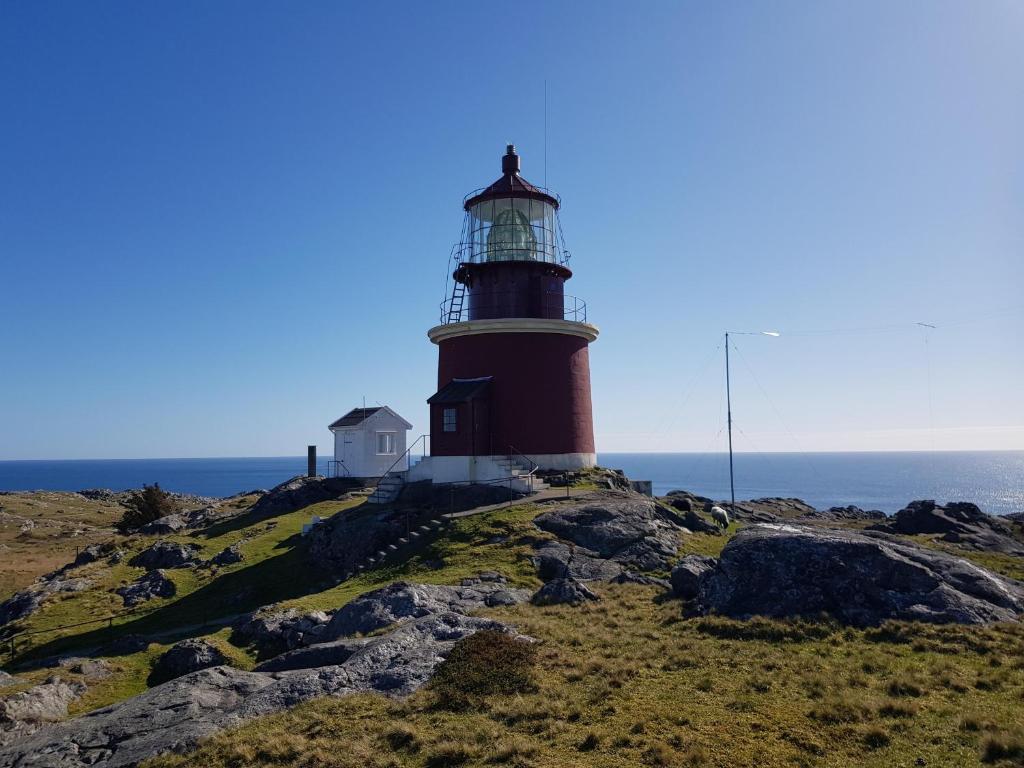 a lighthouse on top of a hill near the ocean at Utsira Overnatting - Fyrvokterboliger in Utsira