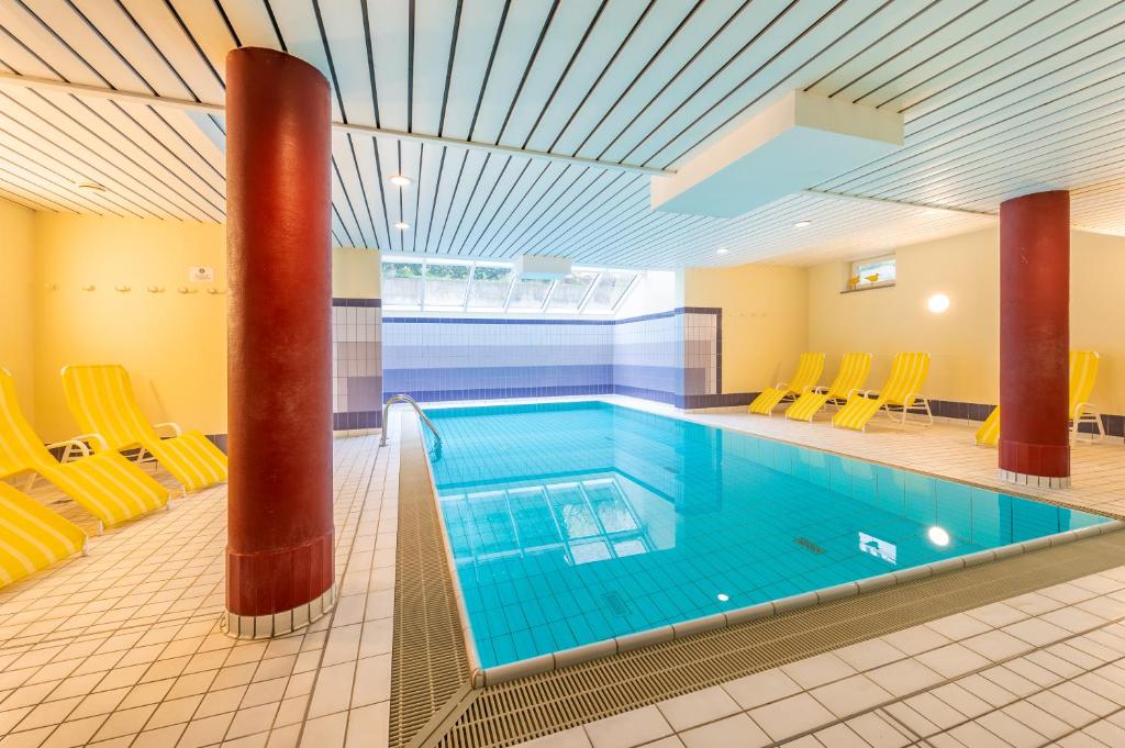 a large swimming pool with yellow chairs around it at Appartment Strandduene in Binz