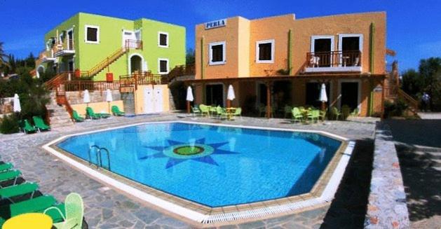 a large swimming pool in front of a house at Perla Apartments in Agia Pelagia