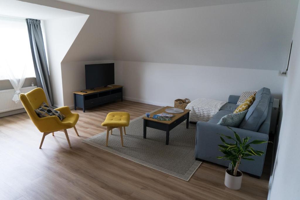 sala de estar con sofá azul y silla amarilla en Ferienwohnung Hallighafen, en Bredstedt