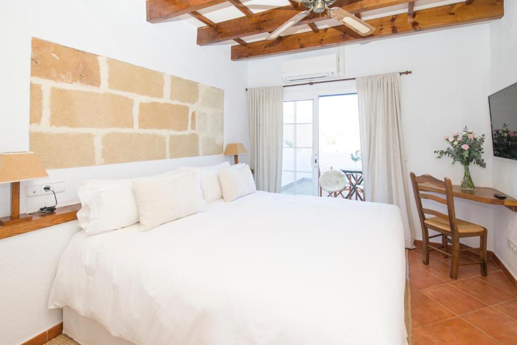 1 dormitorio con 1 cama blanca, mesa y silla en Llucmaçanes Gran Agroturismo en Mahón