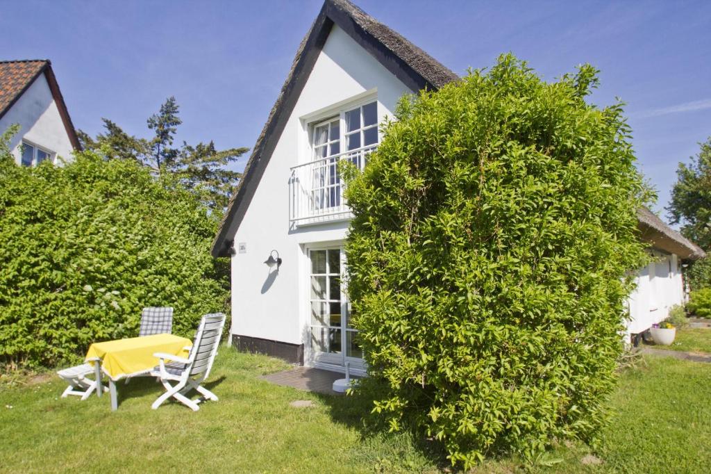 a cottage with a table and chairs in the yard at strandnahe Idylle am Meer, private Badestelle, Strandkorb - Gutshof Ostseeblick in Neuendorf