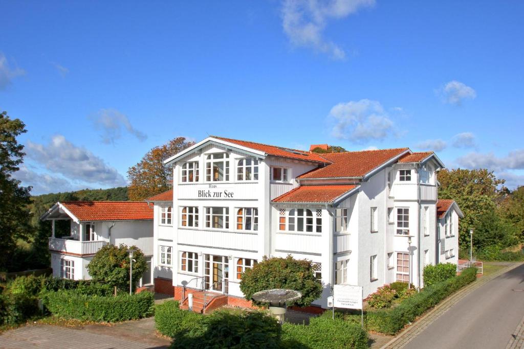 un gran edificio blanco con techo rojo en FeWo mit Meerblick, gratis Nutzung vom AHOI Erlebnisbad und Sauna in Sellin - Haus Blick zur See FeWo 10, en Göhren