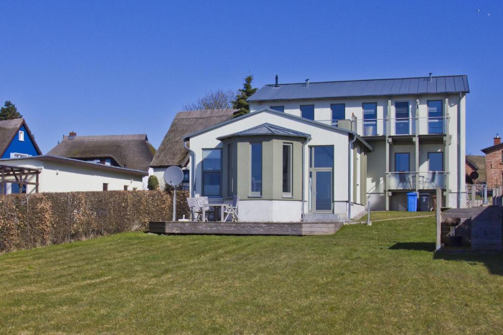 ein weißes Haus mit blauen Fenstern und einem Hof in der Unterkunft Balkon mit Meerblick, ruhige Lage - Ferienhaus Distelfink FeWo 01 in Groß Zicker