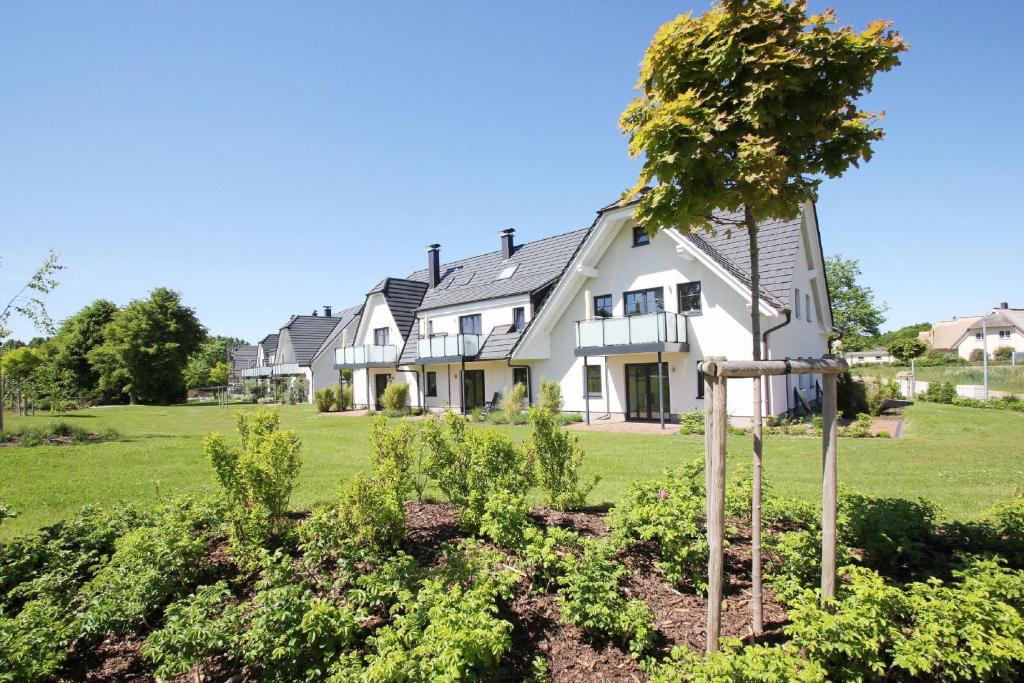 una casa con un árbol en el patio delantero en strandnahe FeWo mit Balkon, gratis Nutzung vom AHOI Erlebnisbad und Sauna in Sellin - Rex Rugia FeWo 11-6, en Lobbe