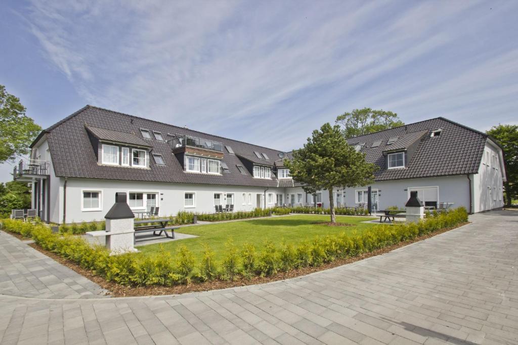 a large white building with a tree in front of it at moderne Ferienwohnung mit Gartennutzung - Haus Inselwind FeWo MEERbucht in Groß Zicker