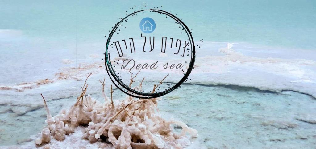 a sign in a pile of sand in front of the ocean at צפים על הים in Neve Zohar