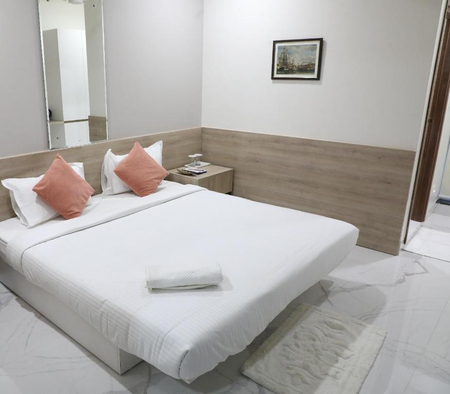 a bedroom with a large white bed with pink pillows at SwanSuites Gachibowli in Hyderabad