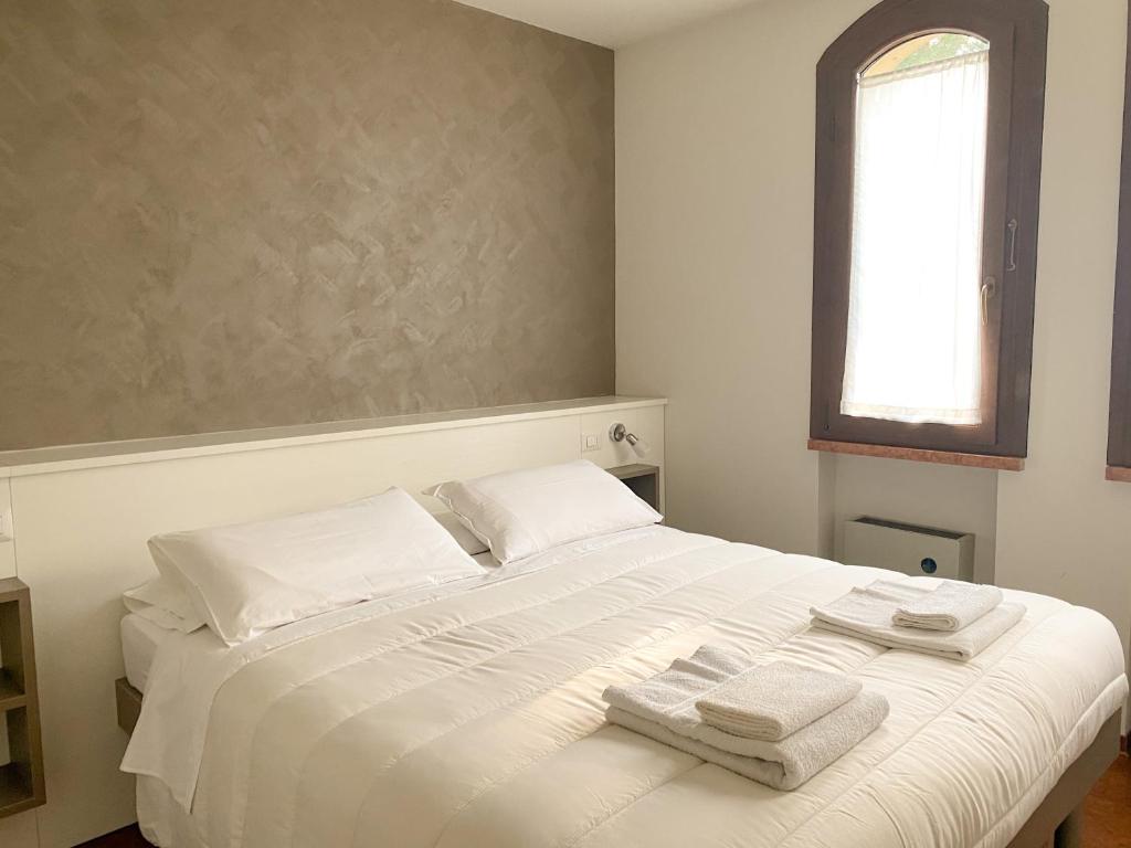 Un dormitorio con una cama blanca con toallas. en Jolly Apartments, en Sirmione