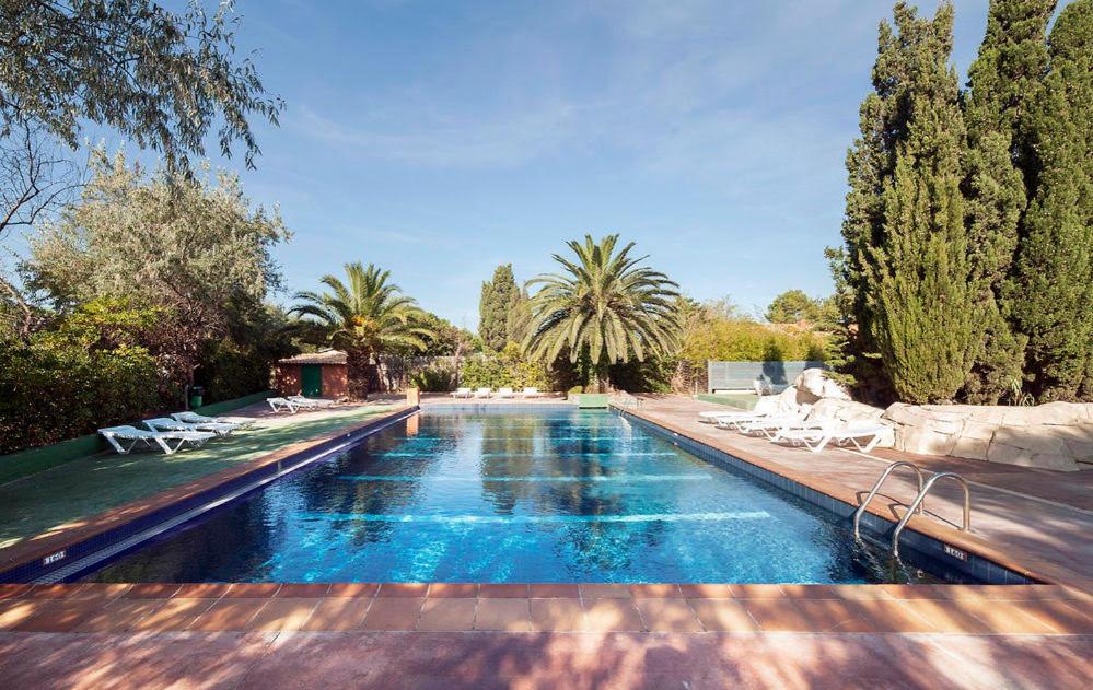 una piscina in un cortile con sedie e alberi di Mobil Home Canet plage a Canet-en-Roussillon