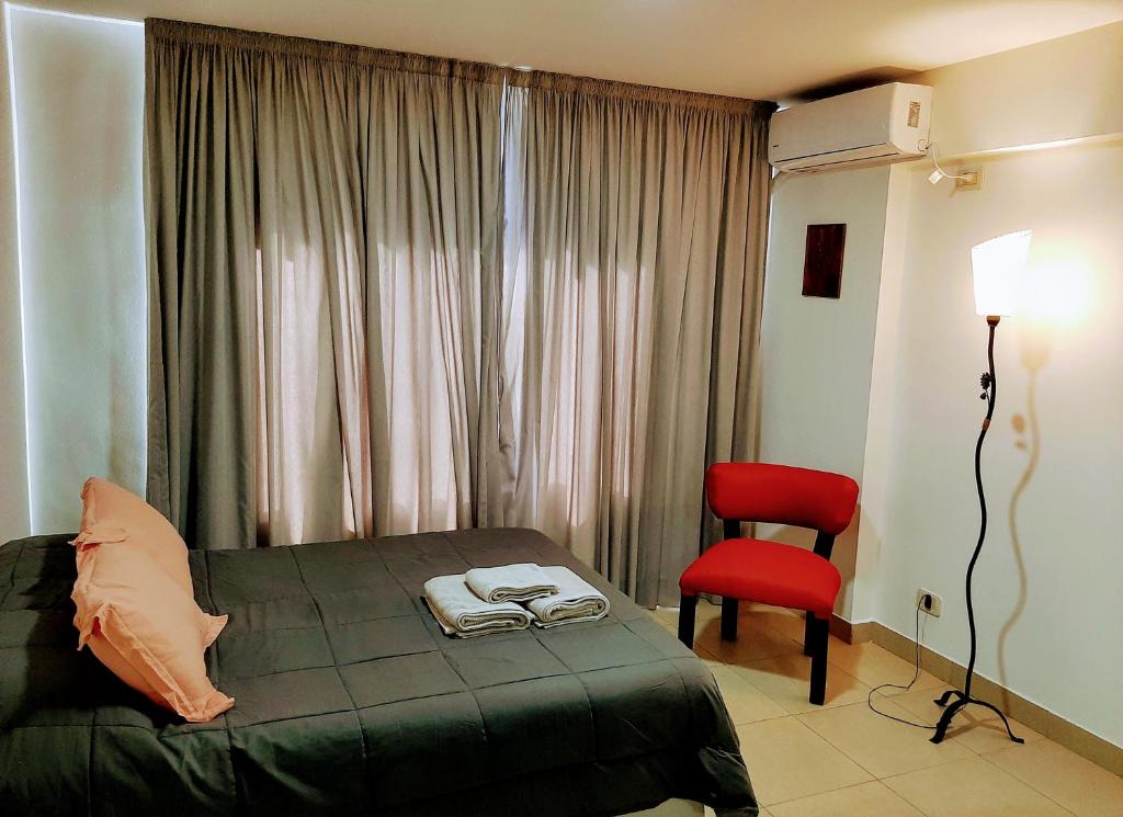 a bedroom with a bed and a red chair at Catamarca Río in Rosario