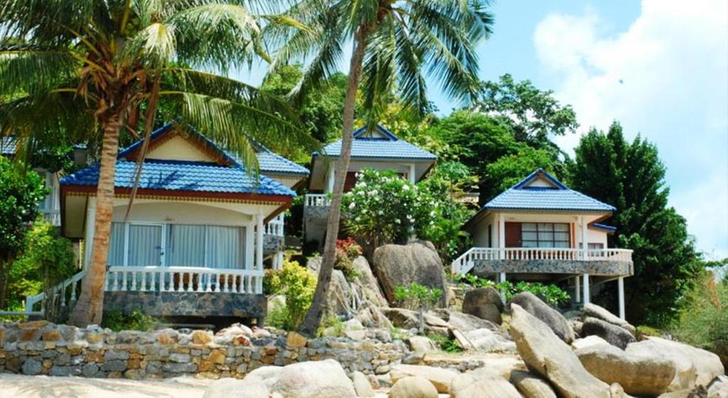 a house on the beach with palm trees and rocks at Phangan Sunset Resort in Ban Tai