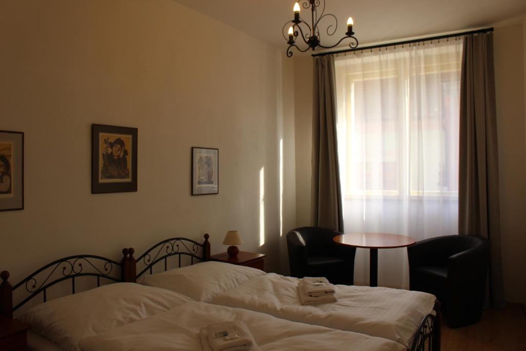 1 dormitorio con 2 camas, mesa y ventana en Hotel Černý kůň, en Louny