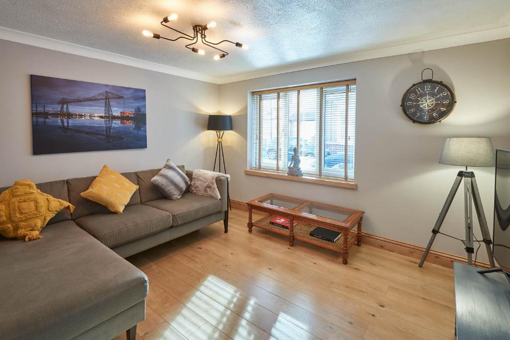 a living room with a couch and a clock on the wall at Host & Stay - Amber Shores in Saltburn-by-the-Sea