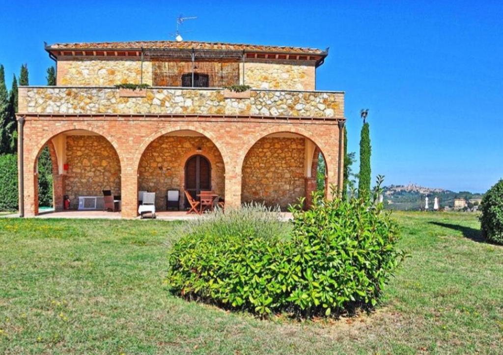 una gran casa de ladrillo en un campo de hierba en Agriturismo Fattoria il Piano - Casa Bugno - San Gimignano, en San Gimignano