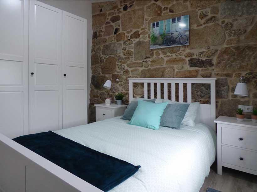 a bedroom with a white bed and a stone wall at CASA VEIGA in Pontevedra