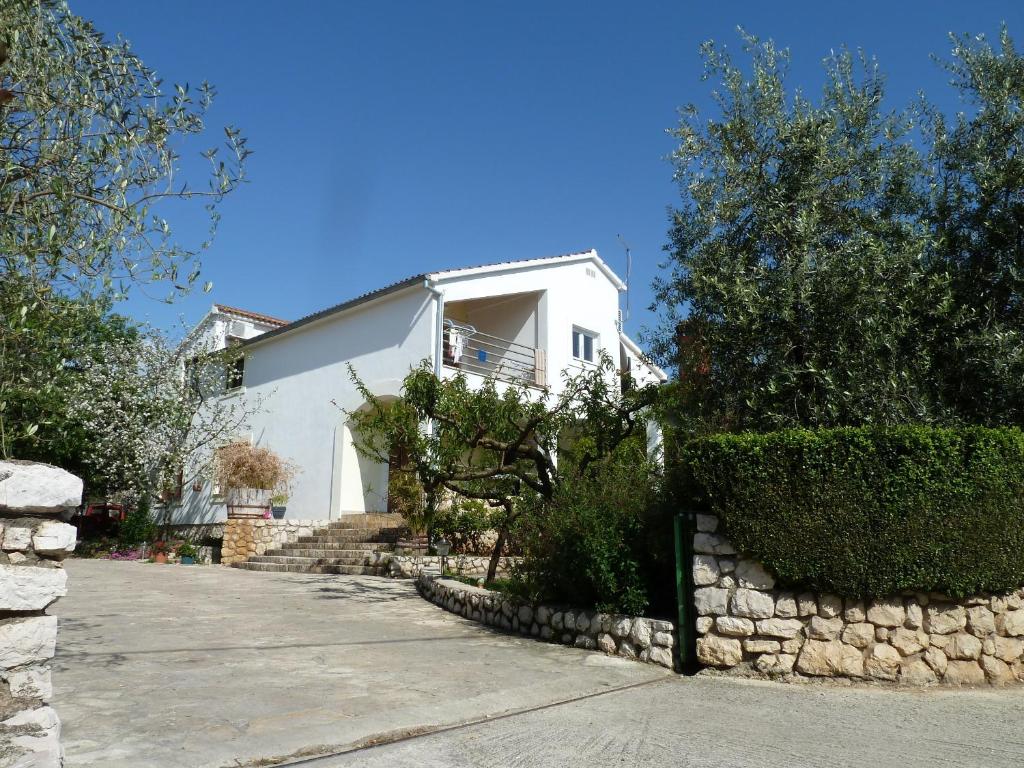 a white house with a stone wall at Apartment Mrkić in Biograd na Moru
