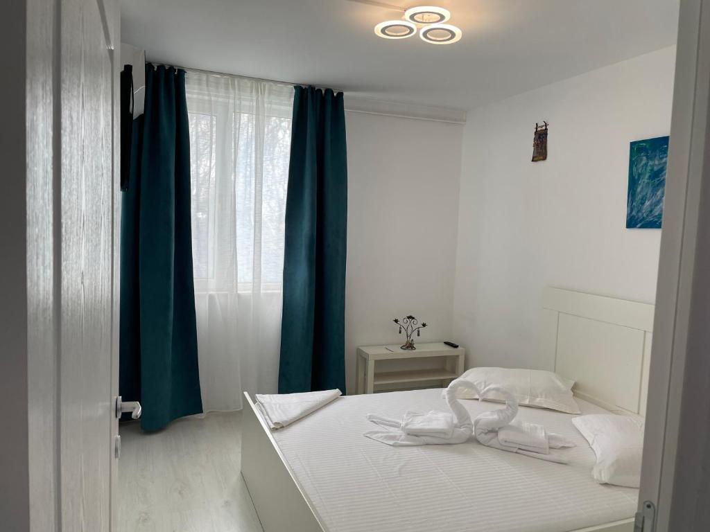 a white bedroom with a bed with blue curtains at Apartament Olimp in Olimp