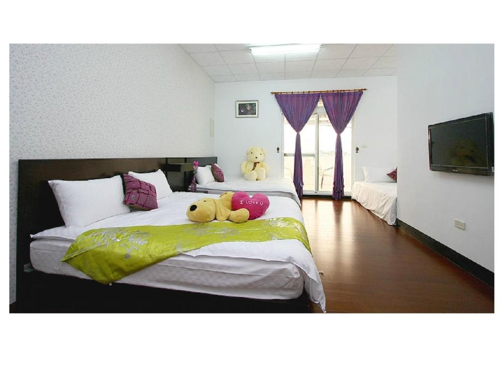 two teddy bears sitting on a bed in a bedroom at Phoenix Walkway Homestay in Taitung City