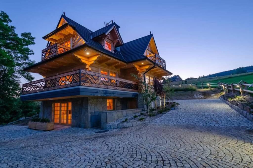 a large log home with a stone driveway at Willa Pitoniówka z sauną, Netflix oraz Xbox one in Kościelisko