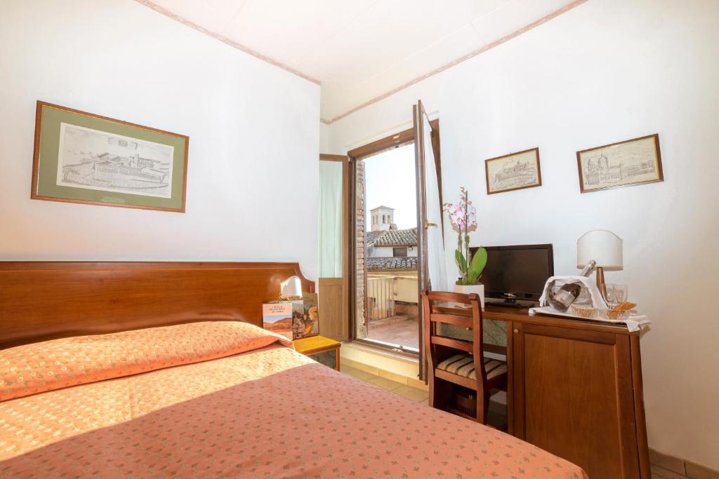 a bedroom with a bed and a desk and a television at Hotel San Pietro in Assisi