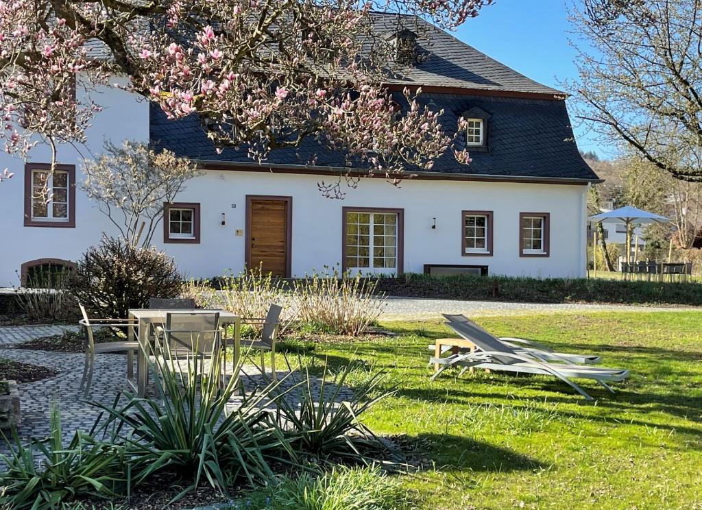 a white house with a table and chairs in the yard at Ferienhaus Martinshof in Traben-Trarbach