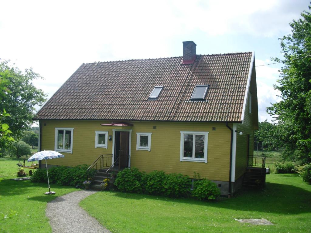a yellow house with an umbrella in the yard at Yxnaholma Rum in Höör