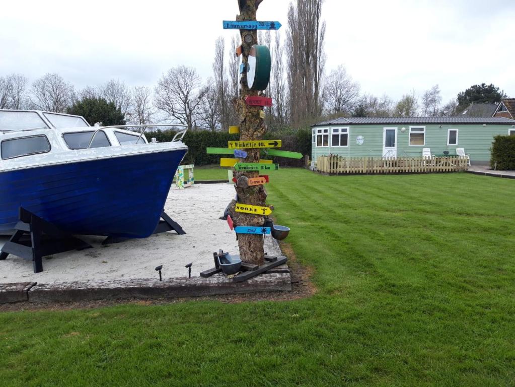 a wooden pole with a boat in a yard at Locatie Het Knooppunt Engelse Chalet in Nuis