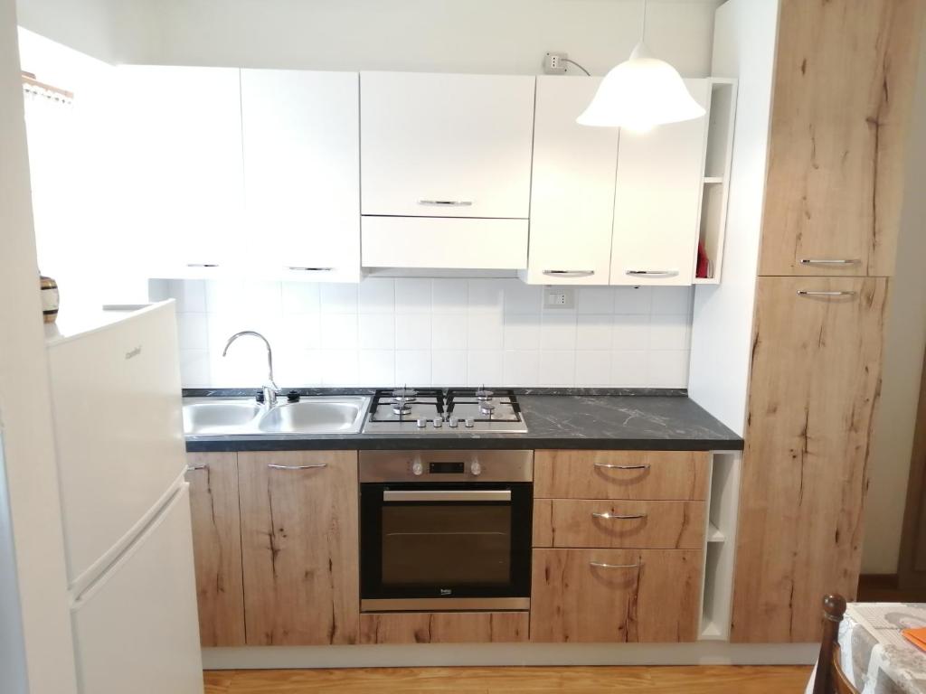 uma cozinha com armários brancos, um lavatório e um fogão em AJARNOLA N14 em Padola