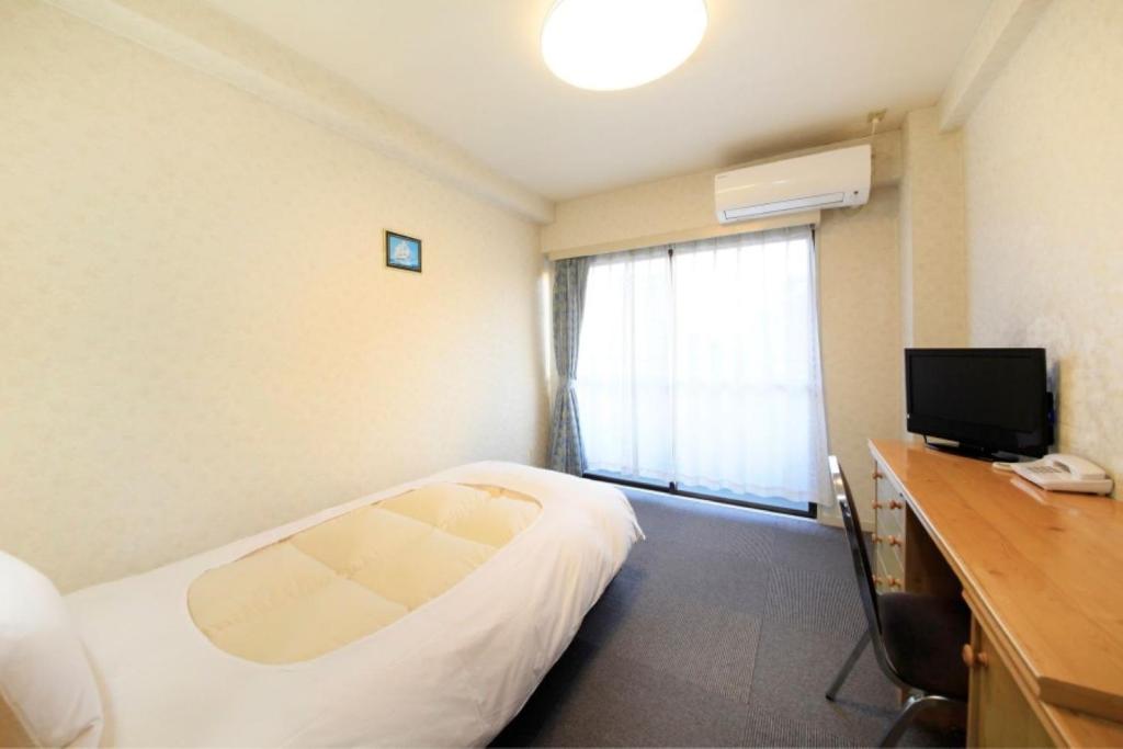 um quarto de hotel com uma cama, uma secretária e uma televisão em Monthly Mansion Tokyo West 21 - Vacation STAY 10861 em Fuchu